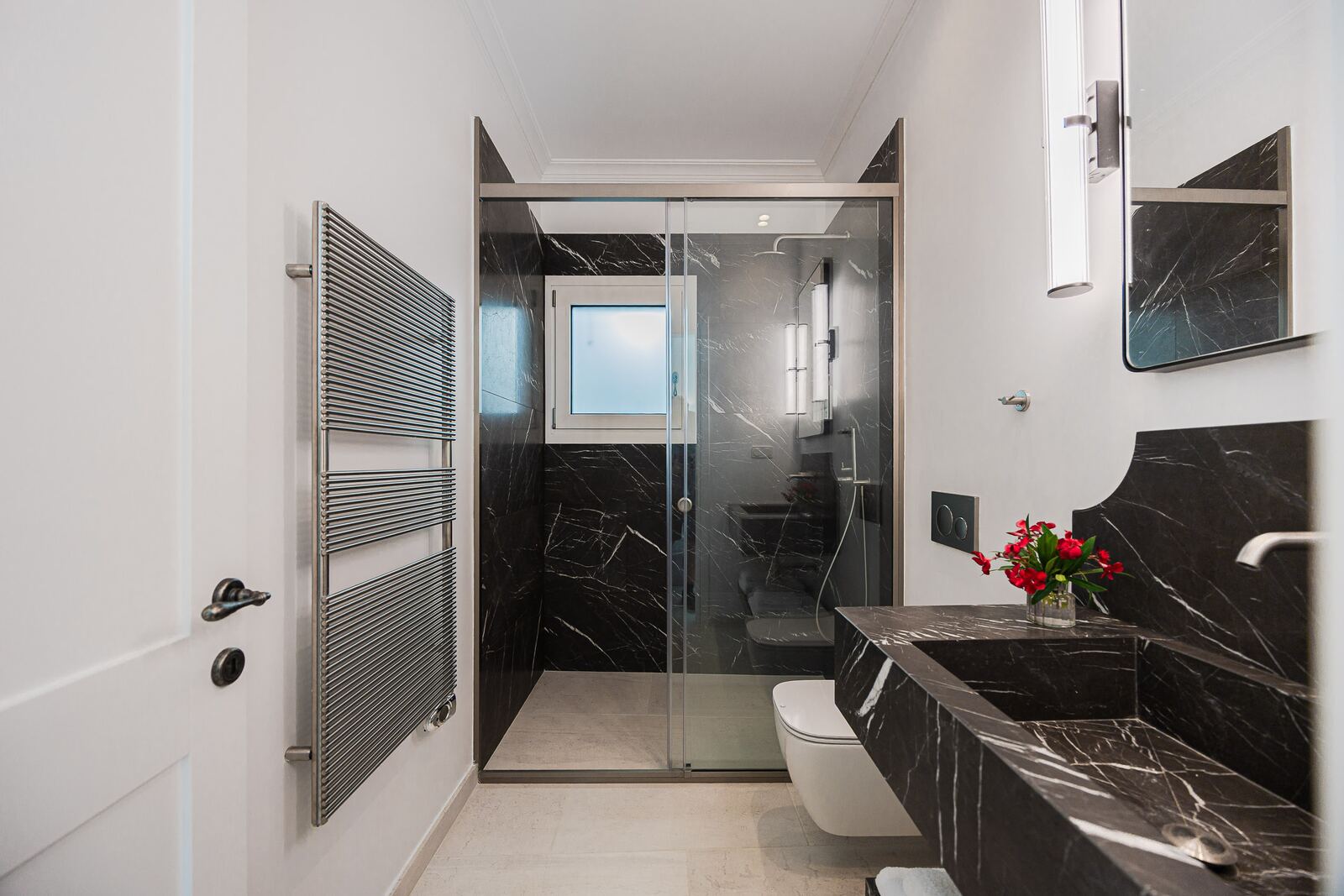 Black marble bathroom with a walk-in glass shower and heated towel rail