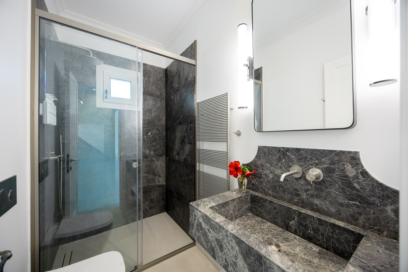 Grey marble bathroom with a solid stone basin and walk-in shower