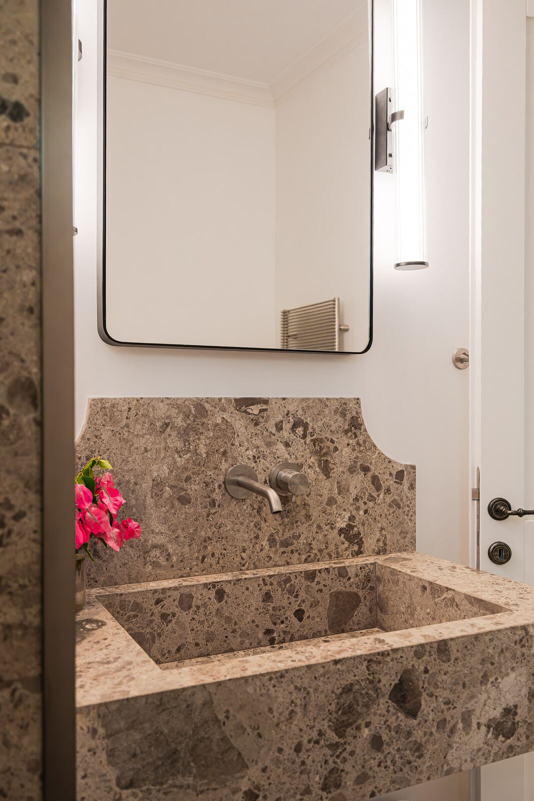 Carved breccia basin with bougainvillea and lit mirror