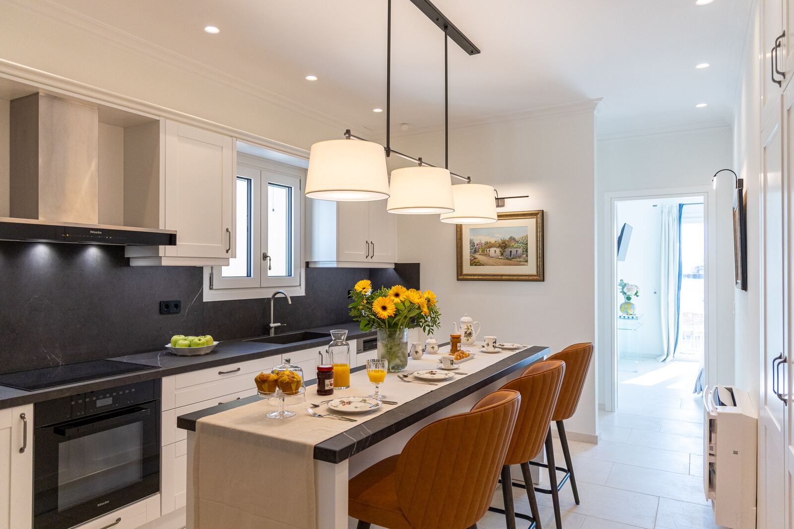 The kitchen seen along its length, with island seating and pendant lights
