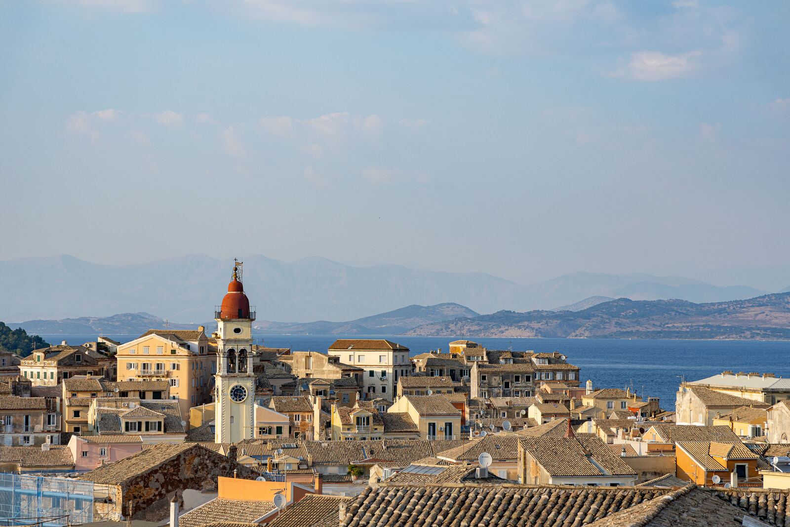 The bell tower of Agios Spyridonas over the tiled roofs, the Ionian beyond